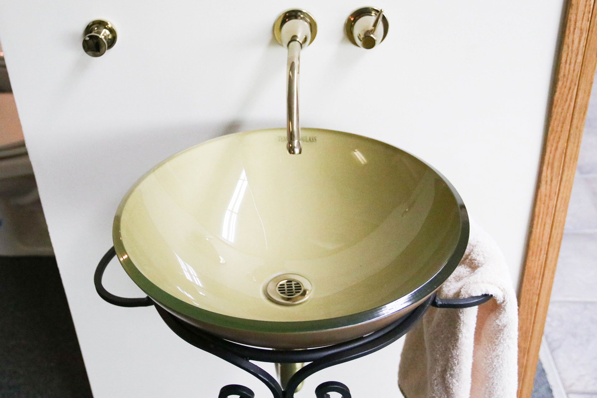 Beige glass vessel sink with faucet.